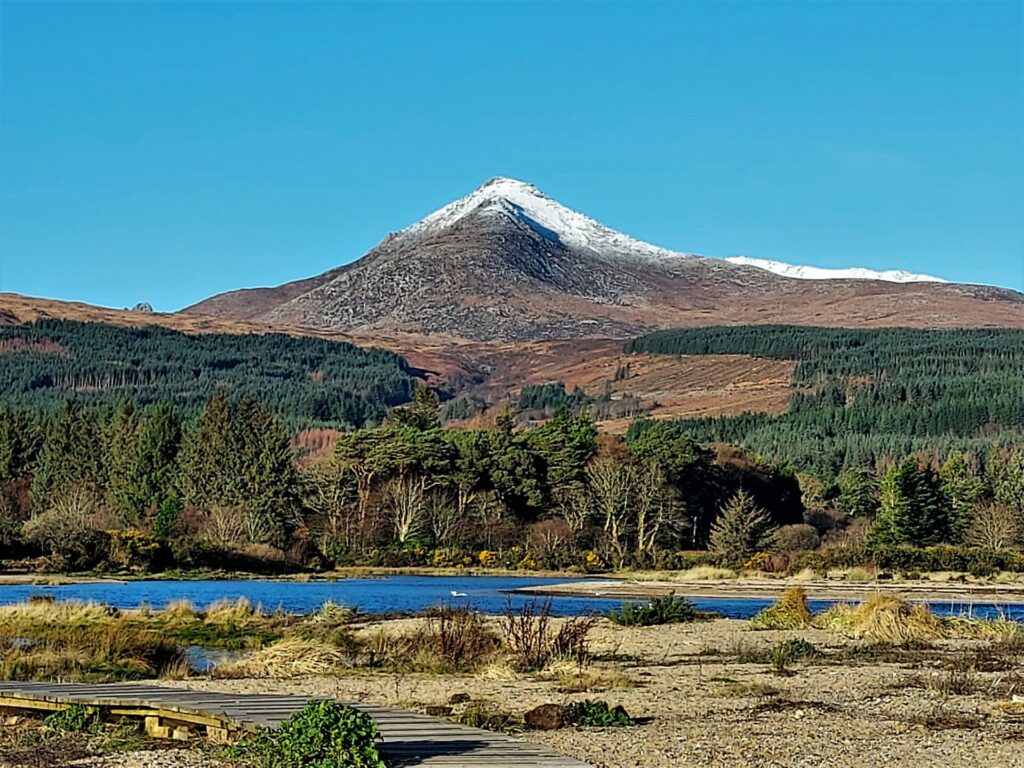 A scenic photo of Goatfell, topped with White Snow, set against a clear blue sky