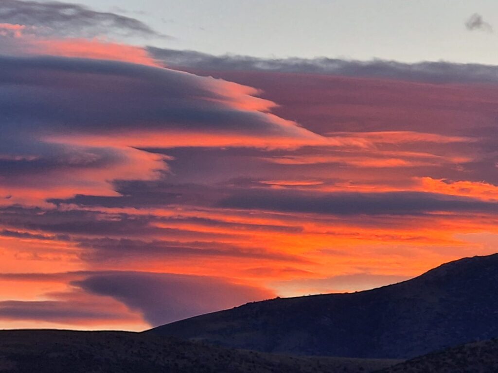 A photo of a very low sun highlighting clouds in hues of orange