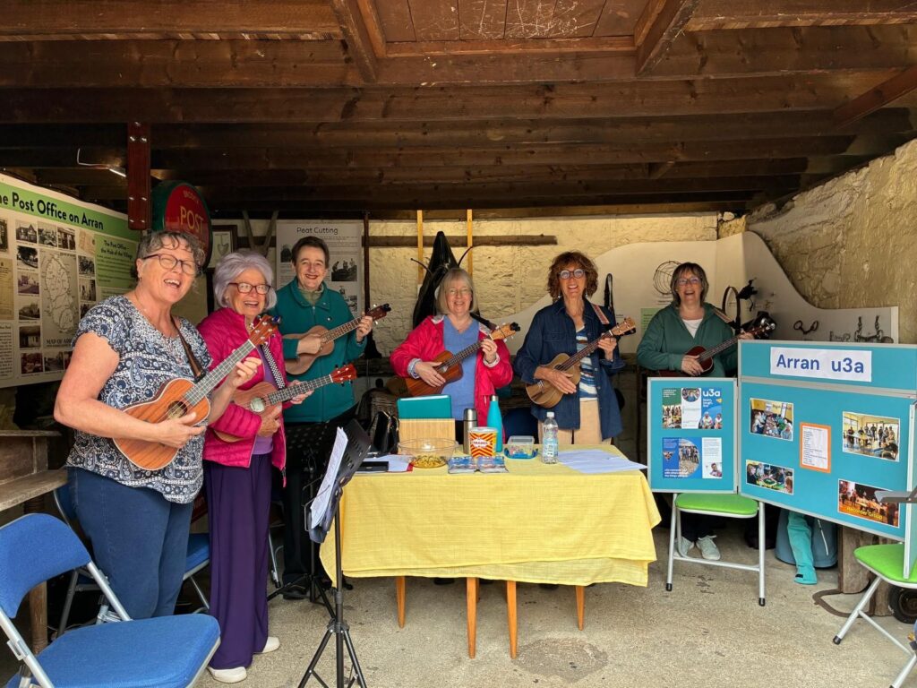 A photo of u3a Ukulele group members entertaining visitors at the Brodick Museum craft day